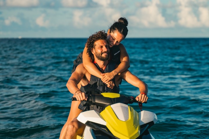 Couple riding a jet ski on open water under a clear sky.